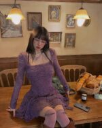 Purple lace gothic aesthetic dress on a table, featuring a square neckline and long sleeves.