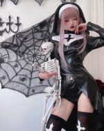 Model wearing a vampire nun cosplay, complete with black dress, skull, and wimple.