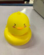 Yellow rubber duck, a kawaii night light, sitting on a white surface.