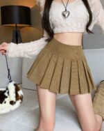 Tan preppy corduroy skirt with pleats, worn by a model.
