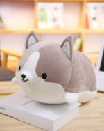 Close-up of a gray kawaii corgi plushie, soft and cuddly, resting on a stack of books.