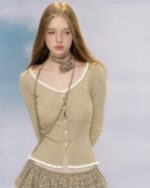 Model wearing a beige vintage aesthetic cardigan with white trim.