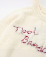 Loose embroidered cat sweater featuring hand-stitched lettering and a cream-colored knit.