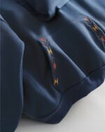Close-up of a navy blue ethno-chic hoodie featuring embroidered geometric patterns.