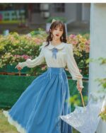 A woman wearing a blue cottagecore dress with lace details, featuring a long skirt and blouse.