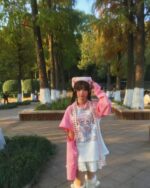 A person wearing a pink kawaii t-shirt with a cute anime design outdoors.