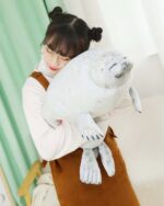 A white yuki the seal plush toy held by a person.