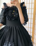 Close-up of a black gothic lolita dress featuring ruffles, lace, and star accents.