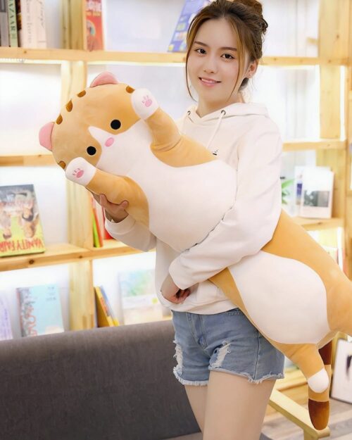 A long cat plushie with tan and cream fur, held by a person.
