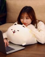 A Kawaii Melonwan plushie, a white stuffed dog, resting on a laptop.