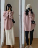 Woman wearing a pink korean style sweater with black leggings and a white skirt.