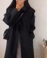 Black Korean style coat worn by a person, showcasing its design and length.