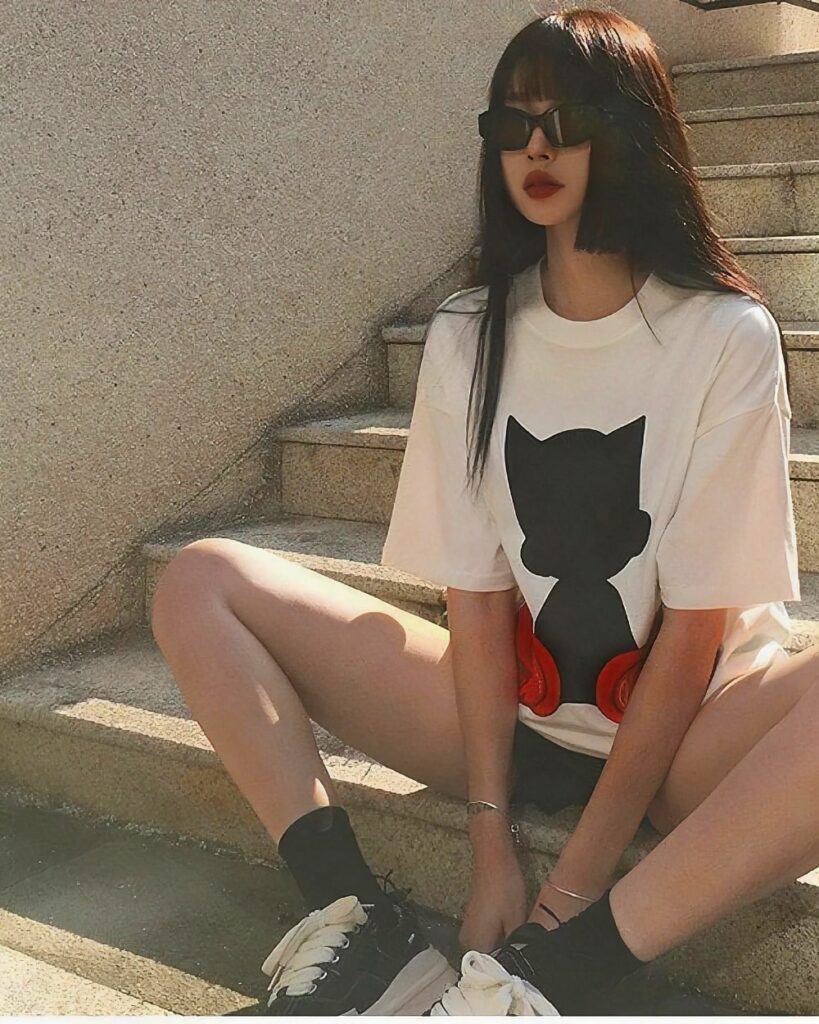 Woman wearing an astro silhouette t-shirt with a black cat graphic on a white background.