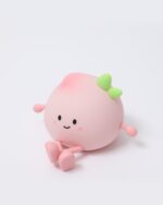 Pink peach night lamp with a smiling face and green accents.
