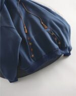 Close-up of a navy blue ethno-chic hoodie with embroidered details and tassels.