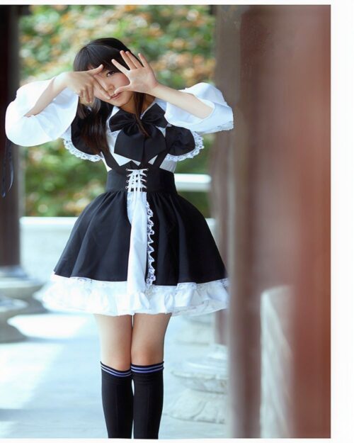 A young woman wearing a black and white classic maid outfit, complete with lace and stockings.