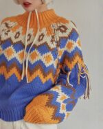 Close-up of a kawaii winter sweater with a colorful, patterned knit and tassel details.
