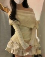 Cream one-shoulder knitwear sweater with a ribbed texture and ruffled skirt.