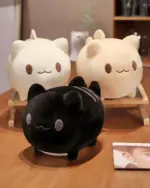 Two round neko plushies, one white and one black, displayed on a table.