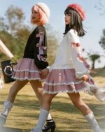 Two women wearing lolita aesthetic sweater with bows and lace skirts, outdoors.