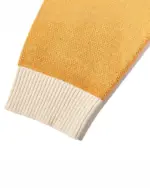 Close-up of a cat reunion sweater sleeve, featuring a ribbed knit cuff in a contrasting beige color.