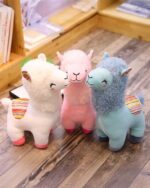 Two Happy Llama Plushies in white and pink, with a third blue llama plushie shown.