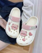 White Piggy Crocs with pink accents and character designs.