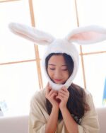 A person wearing a white kawaii bunny ears hat, soft plush material.