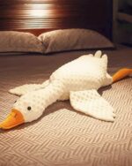 Large white big goose plush toy resting on a bed.