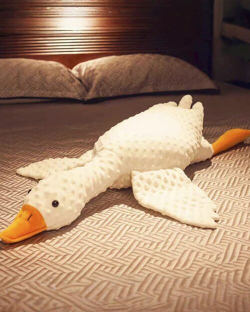 Large white big goose plush toy resting on a bed.