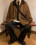 A brown Korean college jacket worn by a person, featuring a corduroy texture and zipper details.