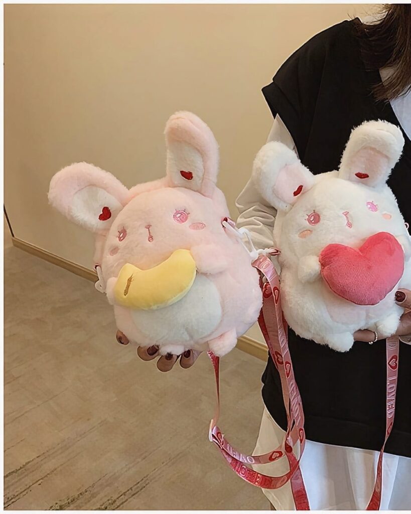 Two pink and white chibi loli handbags with straps, resembling plush toys.