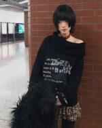 Black grunge aesthetic sweater worn by a person in a public area.