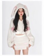Woman wearing bunny hooded plush pajamas, soft white and pink fleece loungewear outfit.