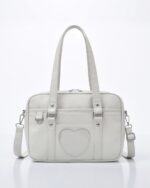 Light gray japanese schoolbag with handles and shoulder strap, featuring a heart shaped pocket.