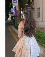 Soft girl dress featuring floral details and ruffles, worn by a person.