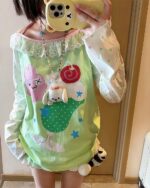 Close-up of a kawaii lime shirt with a pink bunny and green dinosaur print.