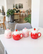 Set of strawberry ceramic mugs with heart designs and strawberry accents.