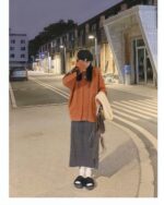 Woman wearing a korean aesthetic sweater on a city street at night.
