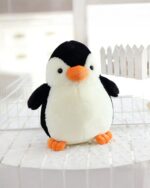 Close-up of a soft, chonky penguin plushie with orange beak and feet.
