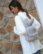Gray plushie rabbit backpack worn by a woman, featuring rabbit ears.