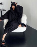 Woman wearing black little devil pajamas with hood and ears. Kawaii decor style.
