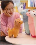 Two Happy Llama Plushies displayed with a woman in a pink sweater.