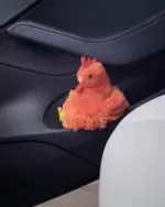 A soft, orange fat chicken plushie sits inside a car door.