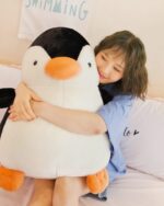 Large, plush chonky penguin plushie, Pip, being held by a person.
