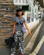 Woman wearing a retro grunge t-shirt and camouflage pants, standing outdoors.