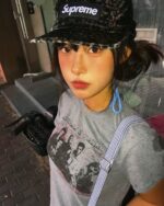 A person wearing a retro grunge t-shirt with a Supreme hat.