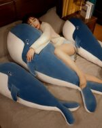 Two kawaii whale plushies, Bubbles and Luna, resting on a bed with a person.