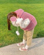 Person wearing a pink kawaii lamb hoodie outdoors.