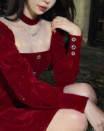 Close-up of a red festive velvet dress with long sleeves and decorative buttons.